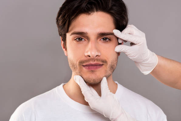 Dr. Lopez personal consultation. Young man with Dr.'s hands describing Mini Facelift procedure.